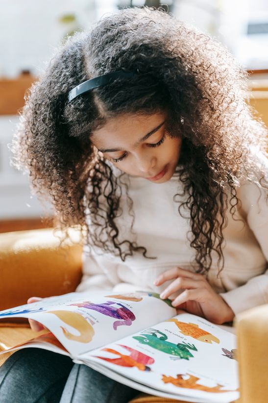 Petite fille concentrée sur un livre illustré