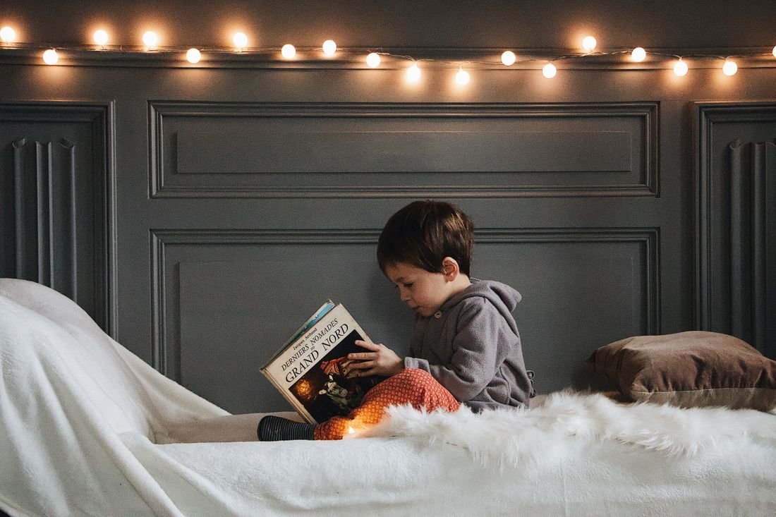Enfant absorbé dans la lecture d'un livre, le soir